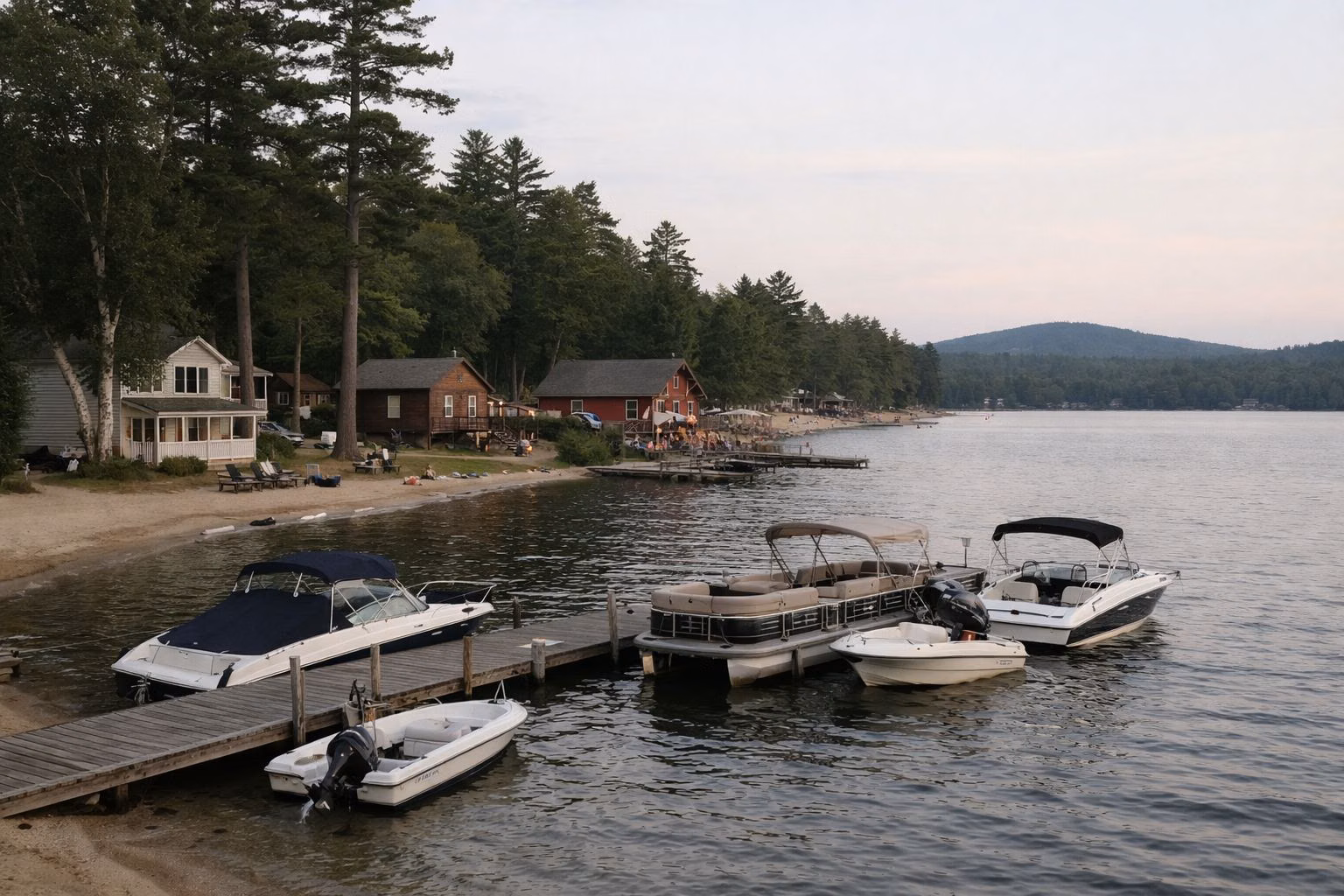 A small lakeside village waterfront with wooden docks, moored motorboats and a few clapboard buildings